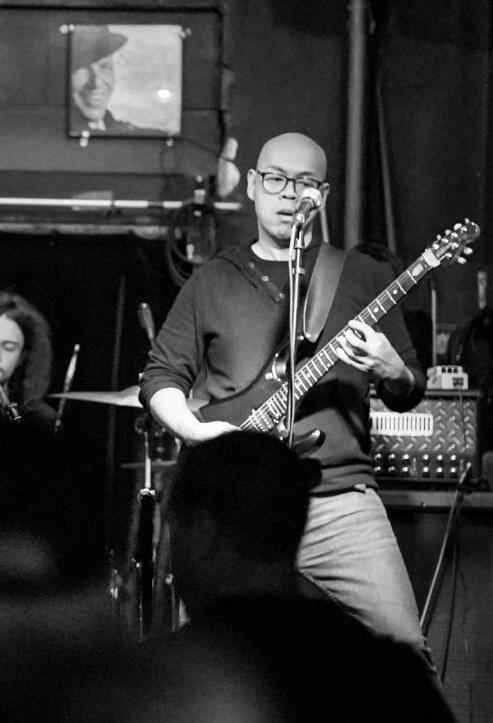 Vinh Diep playing guitar and singing on stage